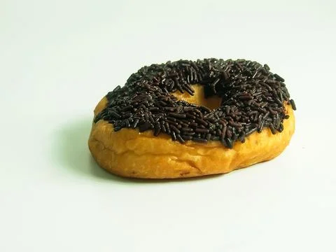 Classic ring donut covered with dark chocolate sprinkles isolated on white .. Stock Photos