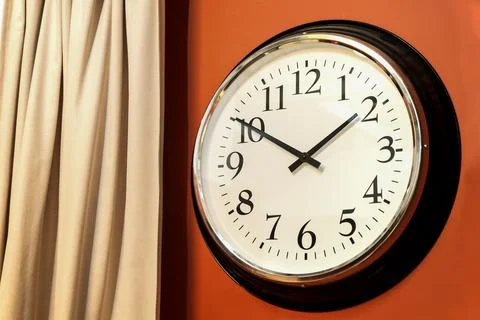 Classic round wall clock in the interior with Arabic numerals, white dial and Stock Photos