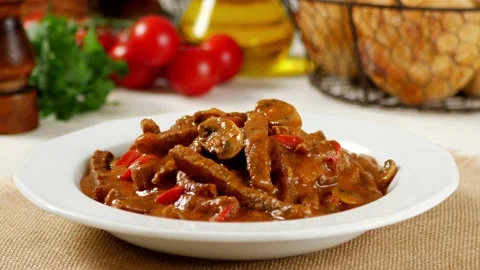 Classic, Russian beef stew. Stroganow. Cook decorates the dish with a cucumber. Stock Footage 133491775