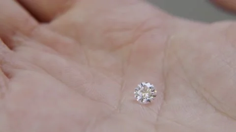 Classic shape of round brilliant cut diamond is held on a hand to show size Stock Footage 154276561