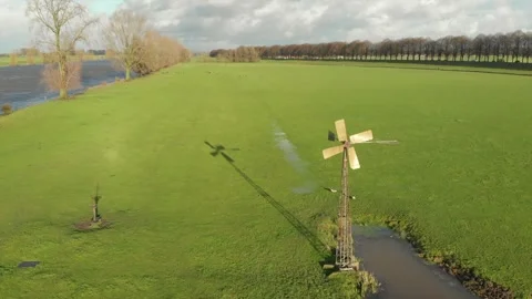 Classic small windmill on a sunny day next to a waterway on high tide Stock Footage 255618904