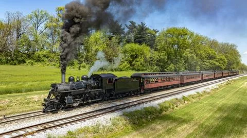 Classic Steam Train Gliding Through Lush Spring Scenery Stock Photos