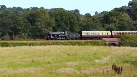 Classic steam train producing smoke travelling through countryside Stock Footage 80323944