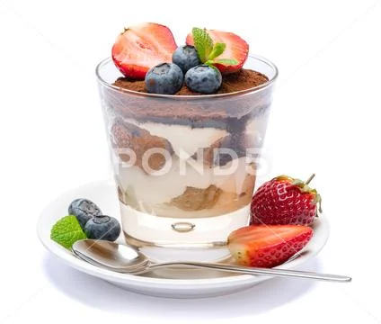 Classic tiramisu dessert with blueberries and strawberries in a glass isolated Stock Photos