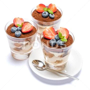 Classic tiramisu dessert with blueberries and strawberries in a glass isolated Stock Photos