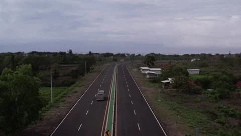 A classic van cruises down a quiet, tree-lined road. Stockbeeldmateriaal 310346166