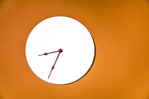 Classic wall clock hanging on an orange wall Stock Photos