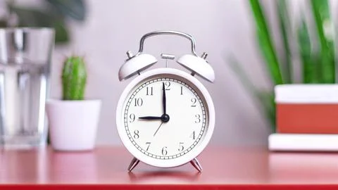 Classic white clock on a table. The clock hand points to 9:00 or 21:00, close Stock Photos