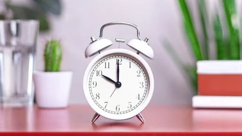 Classic white clock on a table. The clock hand points at 10,00 or 22,00 clo.. 스톡 사진