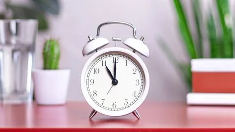 Classic white clock on a table. The clock hand points at 11 or 23 photo inter 스톡 사진