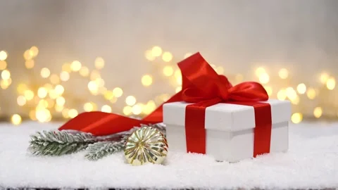 Classic White Gift Box with Red Ribbon on Snow and Twinkling Lights Stock Footage 345561370