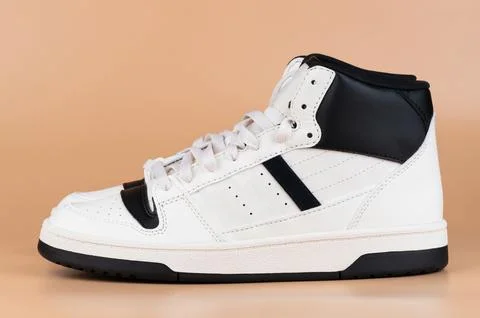 Classic white high-top sneakers with black accents showcased on neutral bac.. Stock Photos