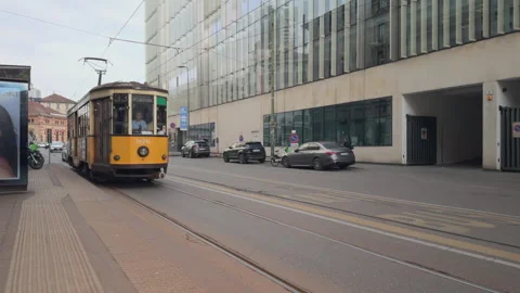 Classic yellow tram arriving at stop in Milan as passengers exit Stock Footage 338243465