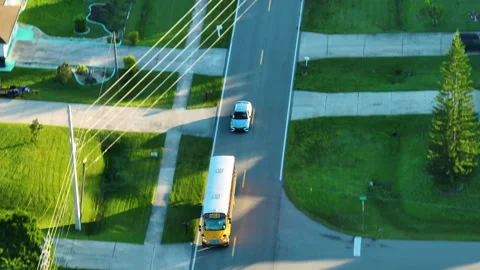 Classical American yellow school bus driving on rural town street for picking up Stock Footage 257424038