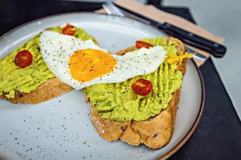 Classical breakfast close up toasts with avocado and sunny side egg Stock Photos