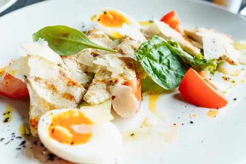 Classical Caesar salad with roasted chiken, eggs, lettuce leaves, parmesan and Stock Photos