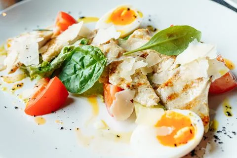 Classical Caesar salad with roasted chiken, eggs, lettuce leaves, parmesan and Stock Photos