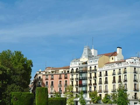 Classical elegant buildings seen though vivid park greenery on Plaza del Or.. Stock Photos