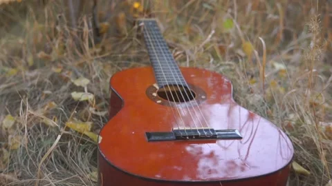 Classical guitar in the shadow lies in the grass Stock Footage 94710653