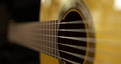 Classical guitar with strings crossing warm golden wood 库存影片 343999426