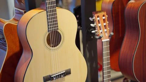 Classical guitars on display in an instrument store, hung on a wall, shot close Stock Photos