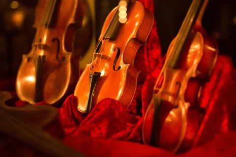 Classical music instruments violins on red velvet illuminated by lights from  Stock Photos