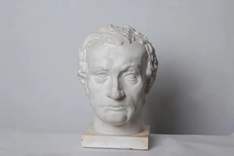 Classical plaster head bust against a white, old, worn wall. Stock Photos