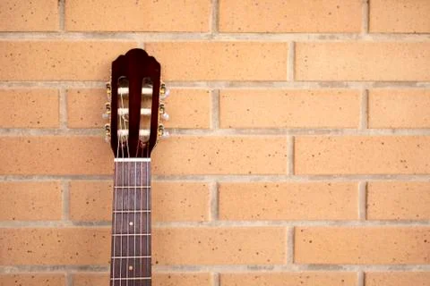 Classical red guitar neck leaning against brick wall Stock Photos