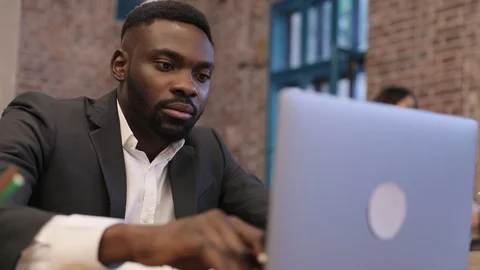 Classically Dressed Afroamerican Using his Computer. Sitting at the Office Table Stock Footage 93907461