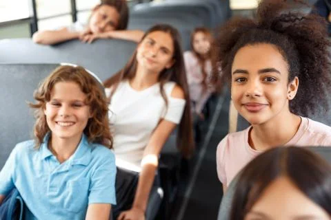 Classmates going to school by bus sitting smiling happy blurred background Stock Photos