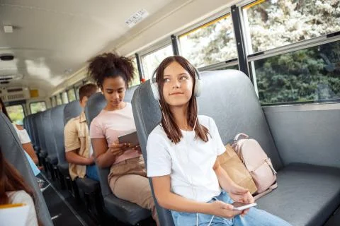 Classmates going to school by bus sitting girl close-up in headphones listening Stock Photos