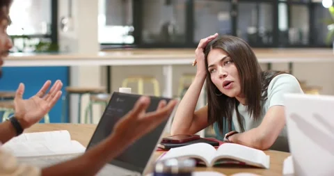 Classmates male peer explaining, female shifting toward interest at study table, Stock Footage 345123849