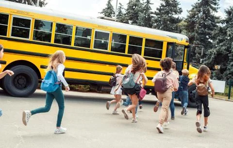 Classmates running to school bus back view late Stock Photos