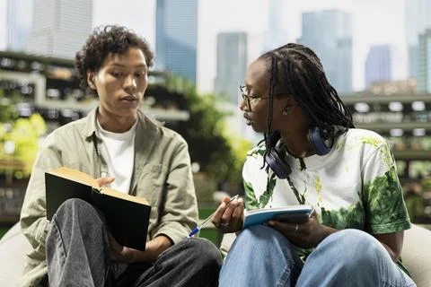 Classmates talking beside open book and textbook on campus for peer tutoring Stock Photos