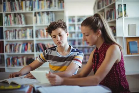 Classmates using digital tablet in library Foto stock