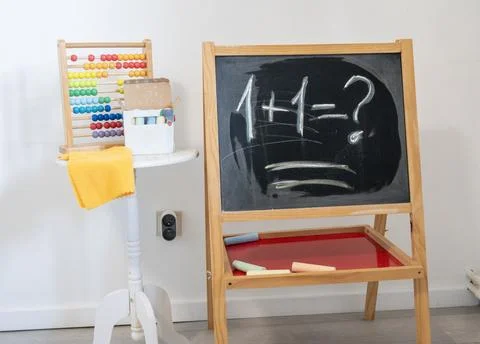 Classroom blackboard with 1 plus 1 chalk math problem,childhood education Stock Photos