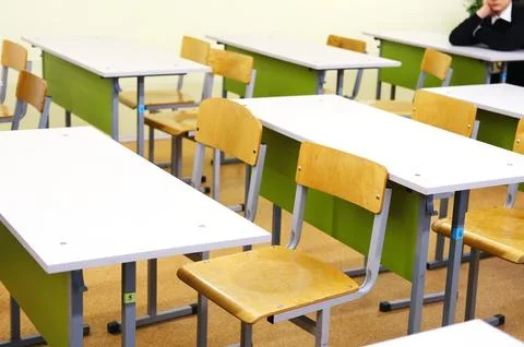 Classroom interior featuring empty wooden desks and chairs arranged in rows Stock Photos