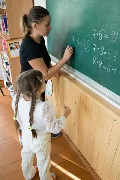 Classroom learning: A teacher writes math problems on a chalkboard while a .. Foto stock