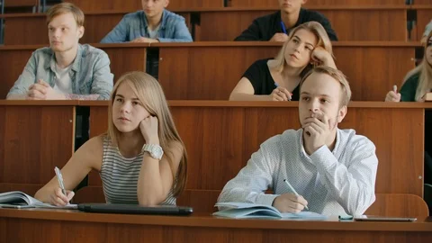 In the Classroom Multi Ethnic Students Listening to a Lecturer and Writing in Stock Footage 116183697