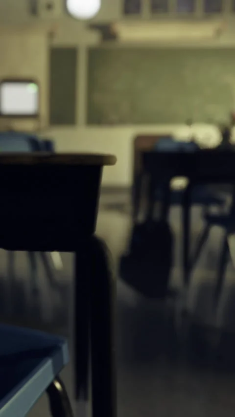 Classroom setting with empty desks and chalkboard present in the background Stock Footage 334174535