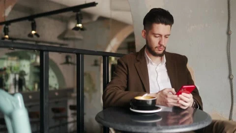 Classy young man using smartphone sitting in cafe. Guy browsing social network Video stock 158733894