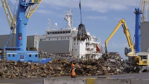 Claw Mechanical construction arm grabber loading ship with scrap on dock Stock Footage 127585155