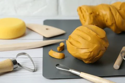 Clay and set of modeling tools on white wooden table, closeup Stock Photos