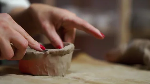 A clay gray ceramic craft for pottery is cutting by woman hand with knife Stockbeeldmateriaal 256323853