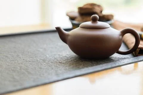 Clay kettle stands on a tea table against a window. Traditional Chinese tea Stock Photos