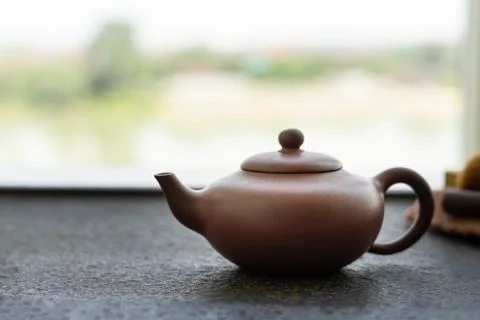 Clay kettle stands on a tea table against a window. Traditional Chinese tea Stock Photos