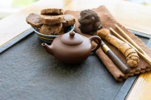 Clay kettle stands on a tea table against a window. Traditional Chinese tea Stock Photos