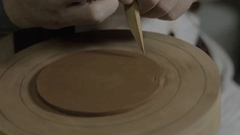 A clay master cuts off an even circle of clay with a wooden knife to make a lid Stock Footage 119066000