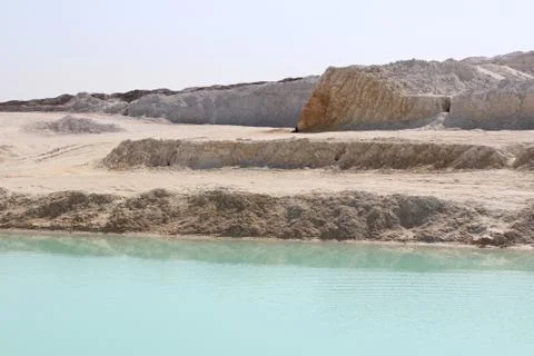 Clay mining. Beautiful background of white clay. Blue water. Stock Photos