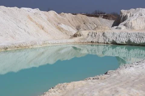 Clay mining. Beautiful background of white clay. Blue water. Stock Photos